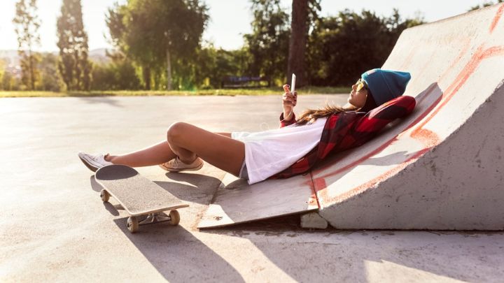 young-woman-with-skateboard-and-cell-phone-in-a-sk-2022-03-08-01-25-52-utc